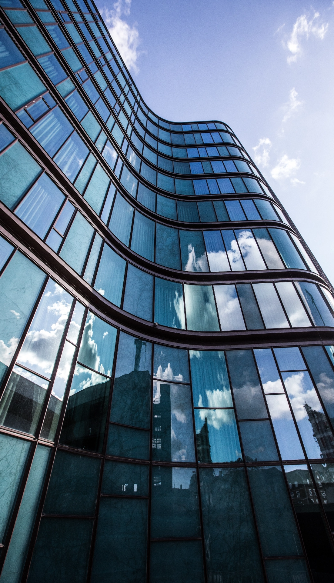 high-rise-building-glass-facade-with-reflection-surrounding-buildings@2x